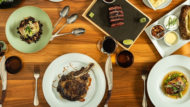 A variety of dishes, including bone-in ribeye and sliced steak, from Bourbon Steak in Miami.