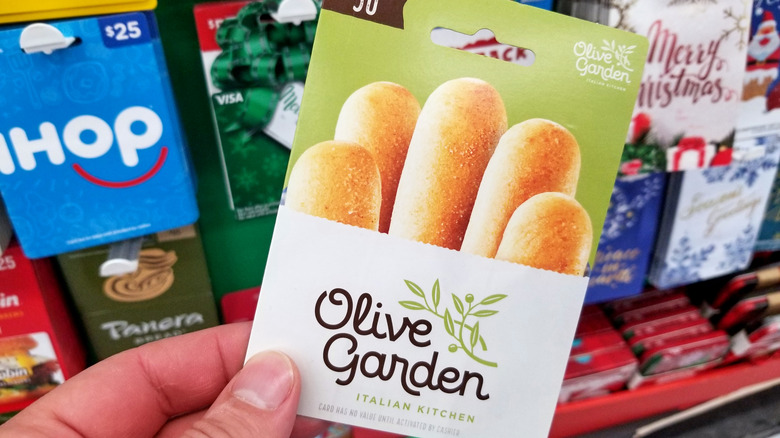Someone holds up an Olive Garden gift card at a store