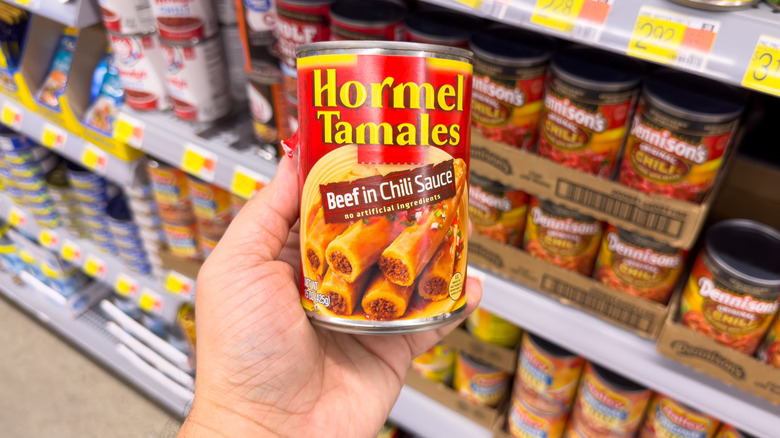 person holding can of hormel tamales at grocery store