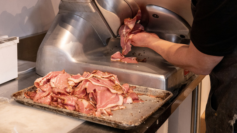 butcher slices deli meat with machine
