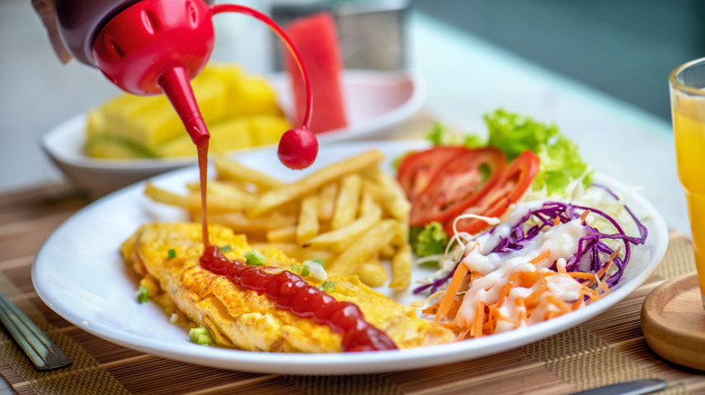 omelet at diner with ketchup being poured onto it
