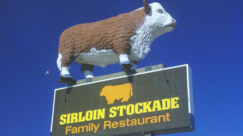 The sign for a Sirloin Stockade family restaurant with a giant cow on top of it