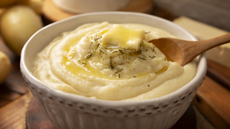A bowl of mashed potatoes topped with herbs and melted butter
