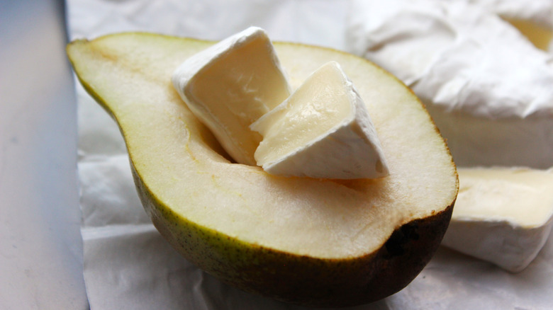 Halved pear topped with wedges of brie cheese