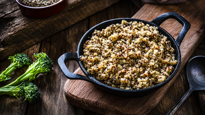 A cast iron container filled with quinoa sitting on a wooden cutting board