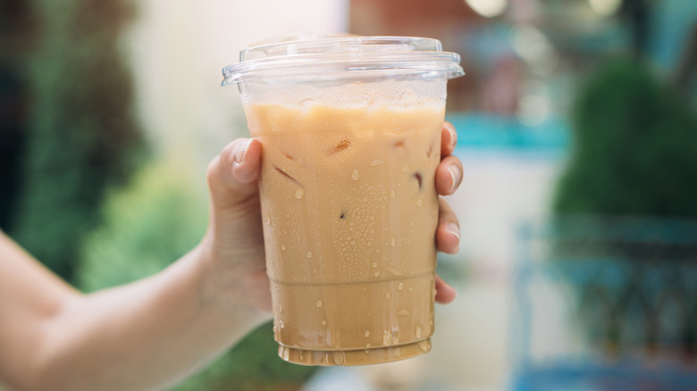hand holding a cup of iced coffee in plastic cup