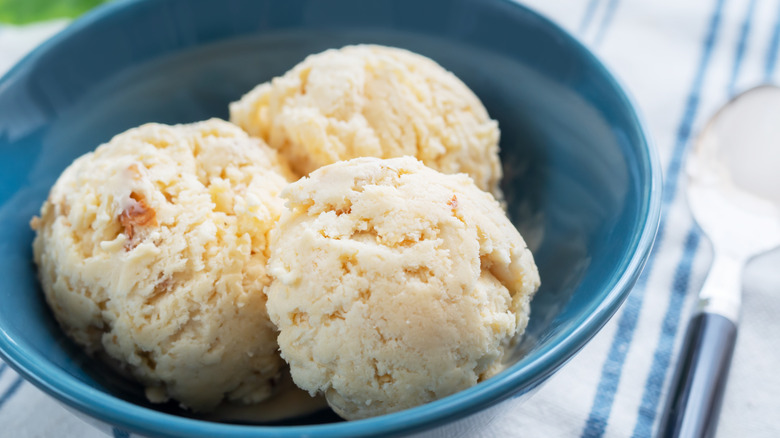 A blue bowl with three scoops of black walnut ice cream sits on a table.