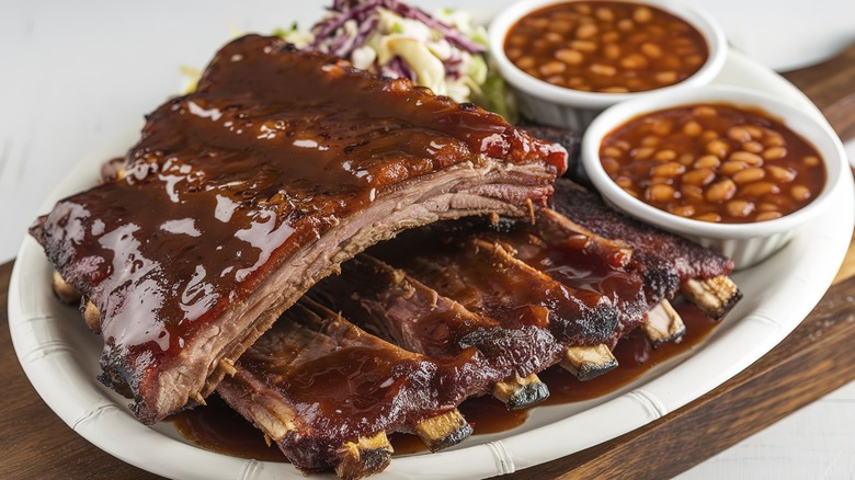 Sauced ribs on a plate with sides of beans and coleslaw