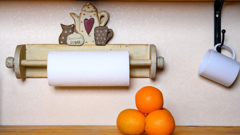 A wooden paper towel holder hangs on a wall.