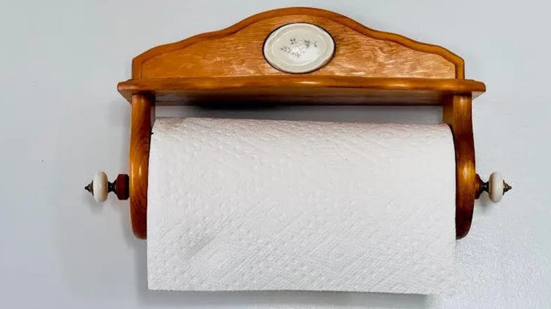 A wooden vintage paper towel holder is mounted on a wall.