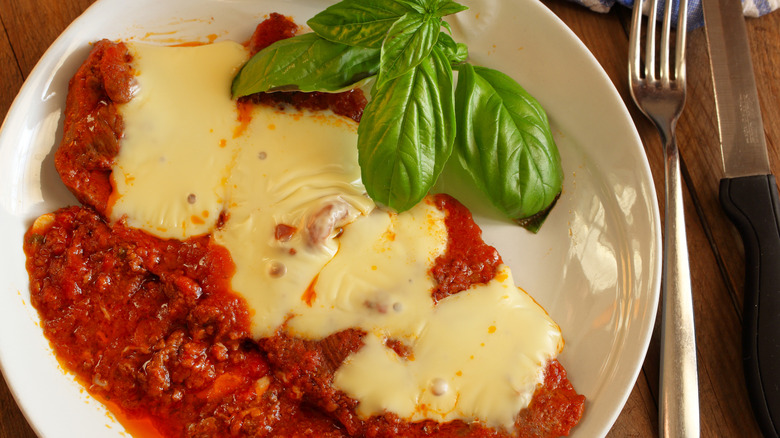 plate of steak pizzaiola with basil and provolone cheese
