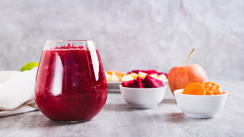 ABC juice in a glass next to bowls filled with ingredients