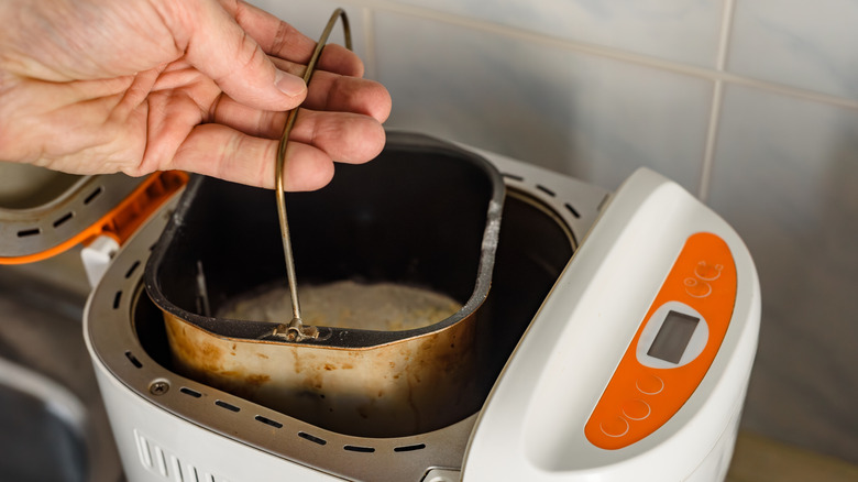 Person using home breadmaking machine.