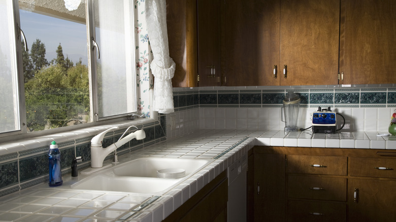 Kitchen with white tiled countertops, tiled backsplash, and dark wood cabinetry.