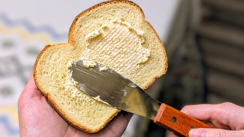 A hand spreading Butternaise on a slice of brioche bread