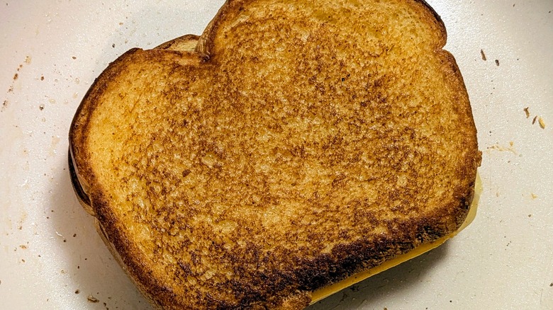 A close-up of a golden grilled cheese sandwich in a white pan