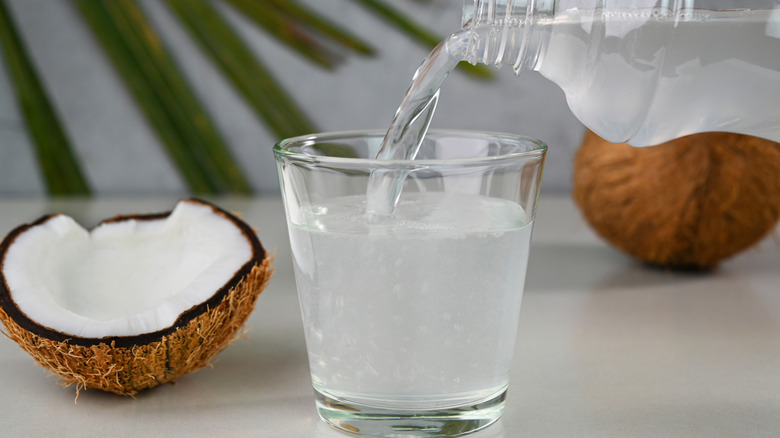 Fresh coconut water pouring into a glass