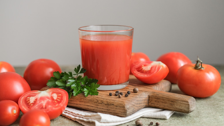Tomato juice in a short glass on a cutting board with chopped tomatoes
