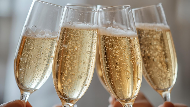Filled Champagne flutes being raised to clink.