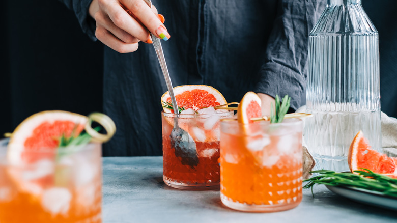 A person prepares colorful cocktails.