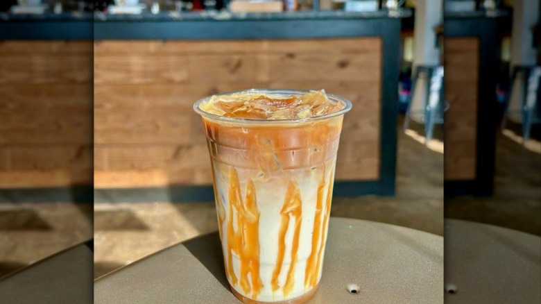 close up of caramel sauce drizzling on the cup of a caramel macchiato at a coffee shop