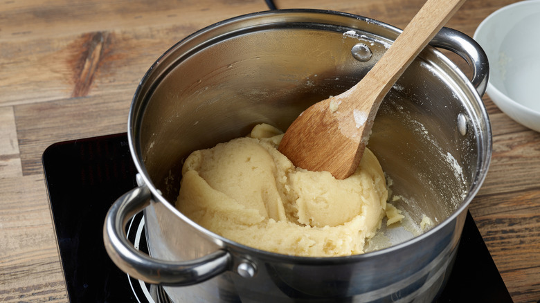 A wooden surface with a pot of eclair dough
