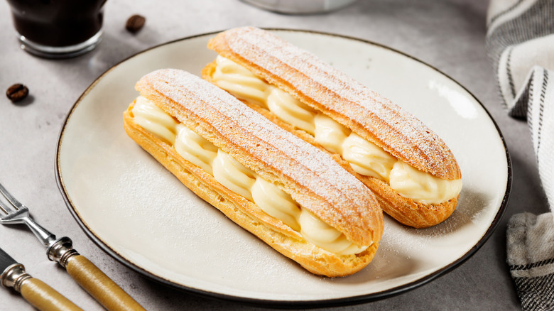 Two eclairs filled with cream on white plate