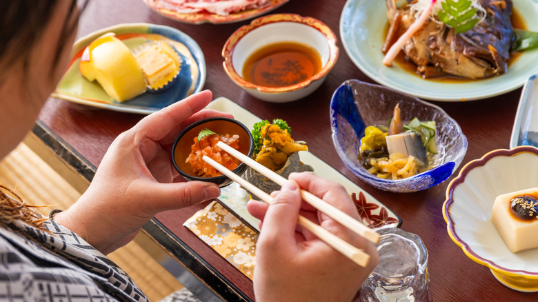 Close above shoulder view of a woman eating a traditional Japanese meal at a ryokan.
