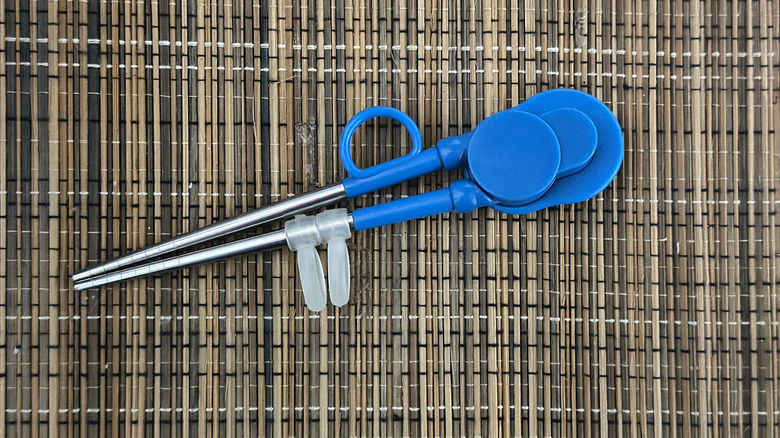 a pair of metal chopsticks with blue plastic handles. These chopsticks are specially designed for beginners or children