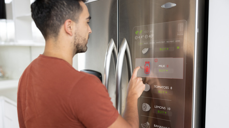 Man using a refrigerator with a built-in touch screen to make a grocery list