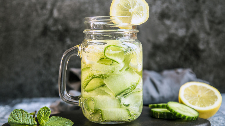 Mason jar of cucumber water on cutting board