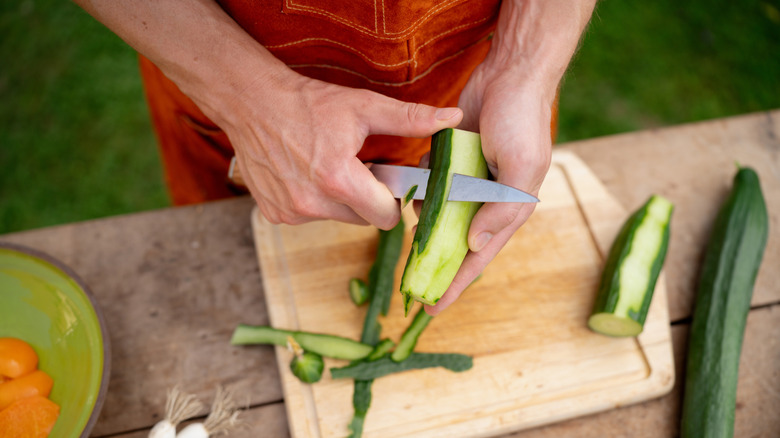 Man peeling a cucumber with a knife