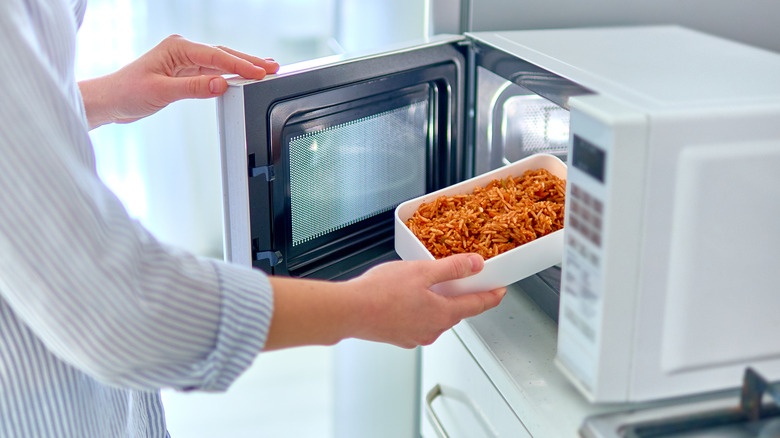 A woman uses a microwave