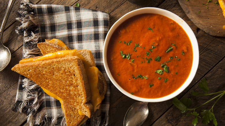 Top-view of homemade grilled cheese beside a bowl of tomato soup