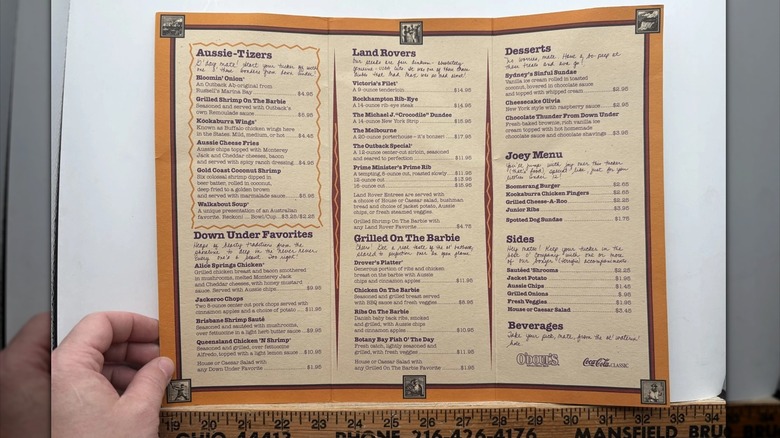 a hand holding a vintage Outback Steakhouse menu from 1994