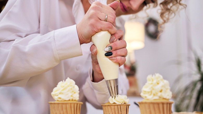 Person piping on cupcakes