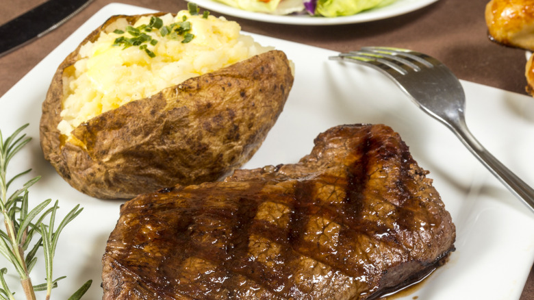 Grilled steak beside a baked potato