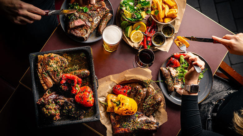 couple at table with grilled meats and veg