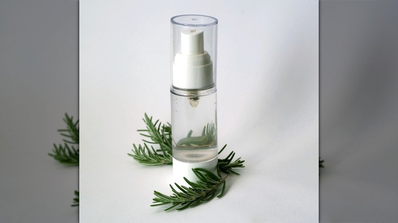 A bottle of rosemary water surrounded by sprigs of the herb