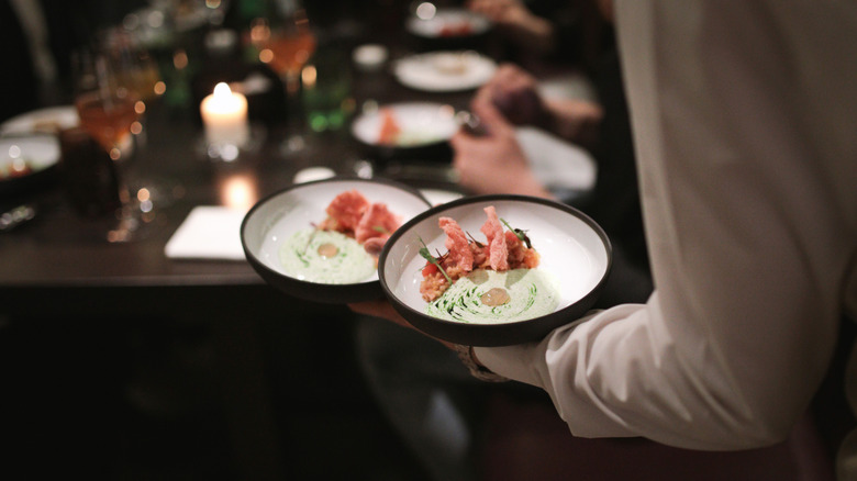 Waiter bringing two dishes to table