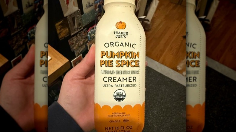 A hand holding Trader Joe's Organic Pumpkin Pie Spice Creamer