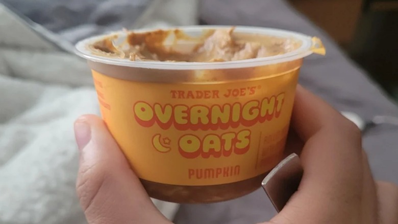 A hand holding a container of Trader Joe's Pumpkin Overnight Oats