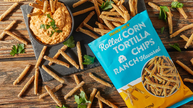 Bag of Trader Joe's Ranch Flavored Rolled Corn Tortilla Chips on serving board with dip.