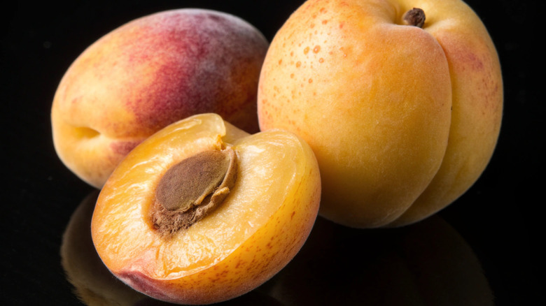 Two whole apriums next to one half sliced to show interior.