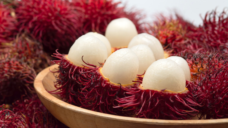 Rambutans, some sliced to show flesh inside.