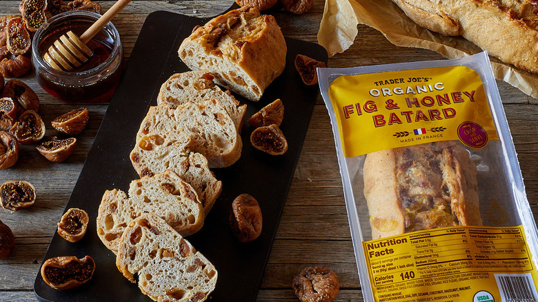 A sliced loaf of Trader Joe's Organic Fig & Honey Batard on a table next to a bag of the bread