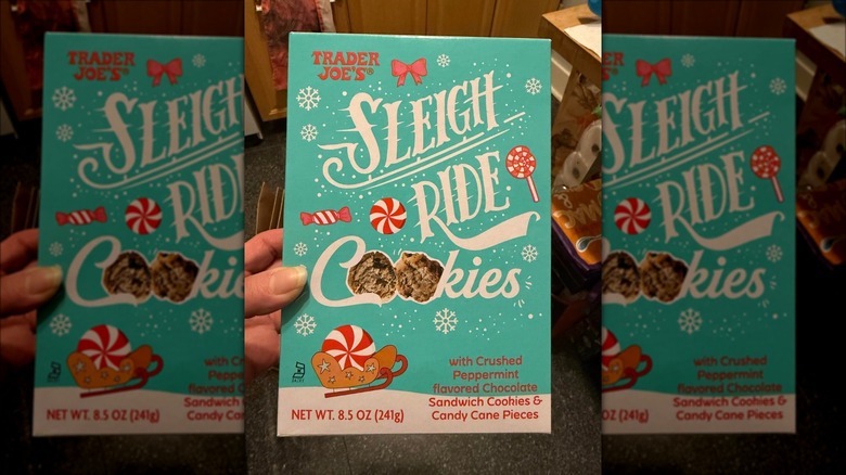 A person holding a box of Trader Joe's Sleigh Ride Cookies