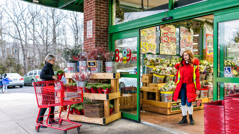 Trader Joe's employee walking out through the exit near shopper with cart