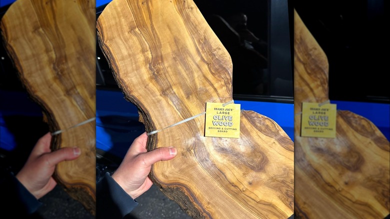 Hand holding big olive wood cutting board from Trader Joe's