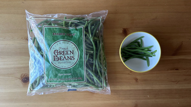 Bag of Trader Joe's Extra Fine French Green Beans next to white bowl of beans on wooden table
